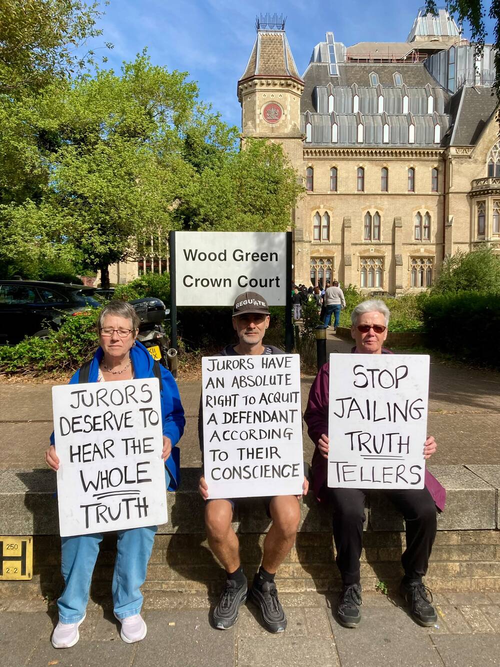 Three campaigners outside Wood Green Crown Court with placards reading "Jurors deserve to hear the whole truth", "Jurors have an absolute right to acquit a defendant according to their conscience" and "Stop jailing truth tellers".
